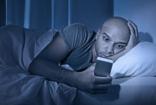 Man staring at phone in bed 
