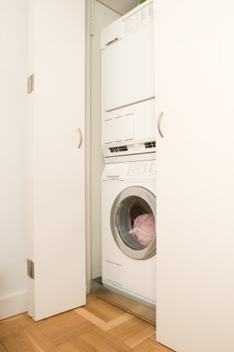 Stackable Laundry Setup Behind Folding Doors in Closet