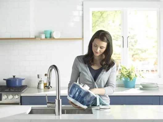 Woman with dark hair standing at kitchen island sink cleaning out humidifier tank