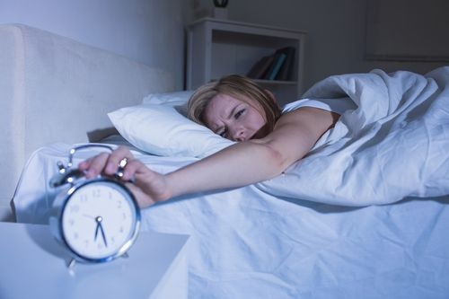 Woman angrily turning off alarm clock 