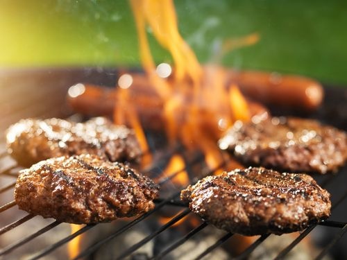 Grill with burgers and hot dogs cooking