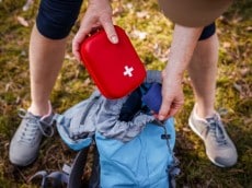 Person loading first-aid kit into backpack
