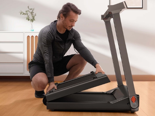 A man unfolding a foldable treadmill.