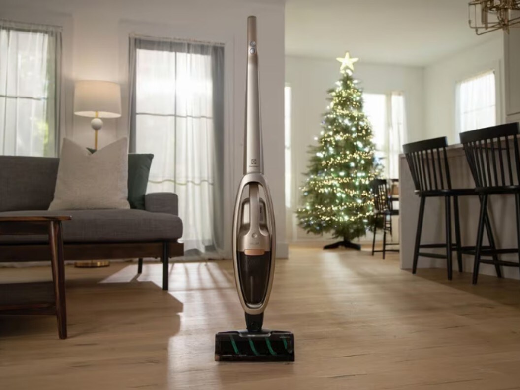 An image of a vacuum cleaner on a hardwood floor with a Christmas tree in the background.