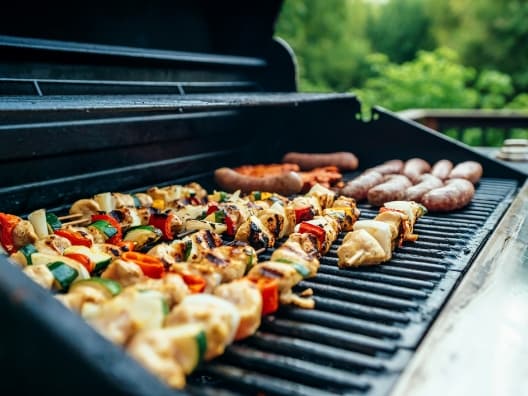 Various foods being cooked on a gas grill