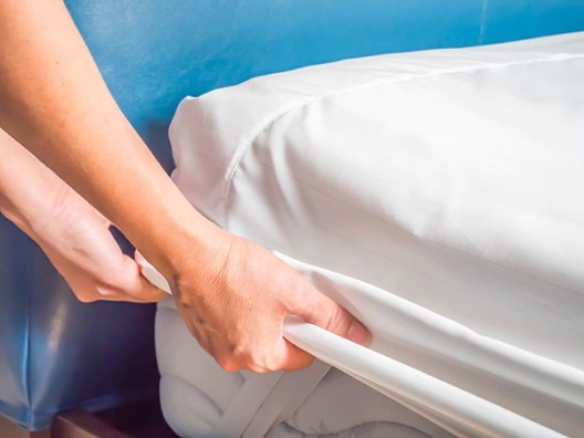 A mattress protector being stretched over a mattress