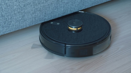 A robotic vacuum cleaning under a couch.