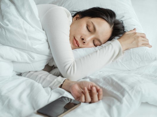 A woman peacefully asleep on fluffy white bedding