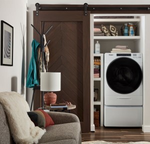 A combo washer dryer in a laundry alcove off a living room