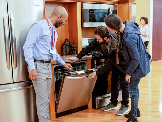 Man and woman looking at dishwasher while sales associate