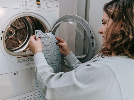 A woman loading clothes into a dryer.