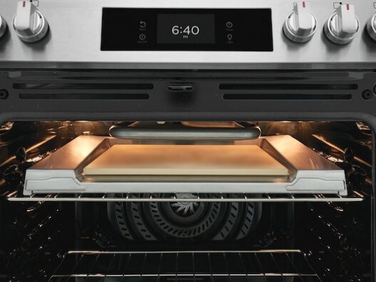 Open oven displaying pizza stone on top rack
