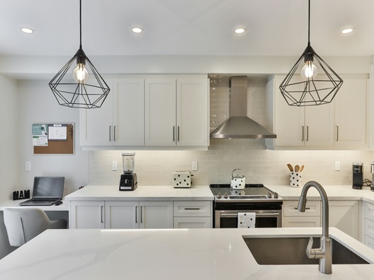 An apartment kitchen with a laptop setup next to one of the counters.