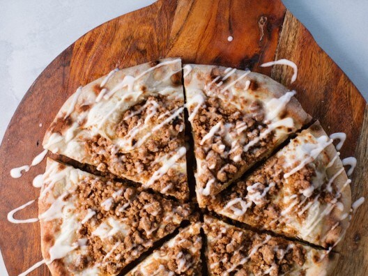 Overhead view of dessert pizza covered in streusel topping and cream cheese drizzle