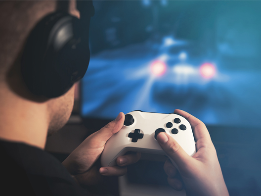 A man wearing a headset and using a controller to play a video game on the TV in front of him.