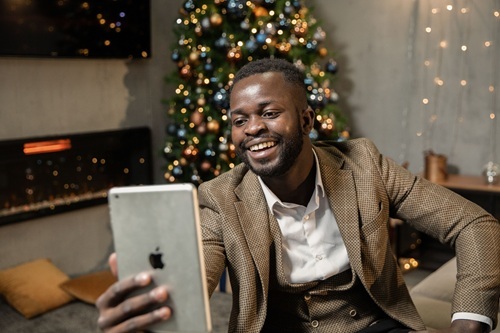 A man holding an iPad in front of a Christmas tree.