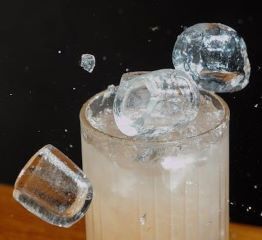 Action shot of a few pieces of bullet ice being tossed into a glass