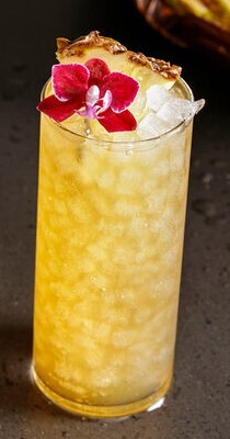 Tropical beverage garnished with a flower and a pineapple piece, filled with nugget ice