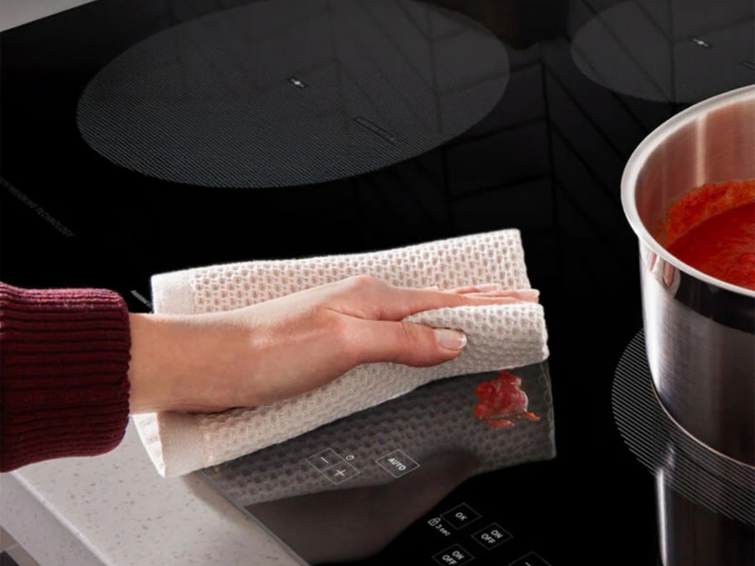 An image of someone wiping up a spill on their induction cooktop.