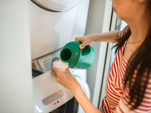 A person measuring out a capful of laundry detergent.