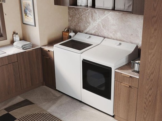 A washer and a dryer sitting snug in against the wall in a laundry room.