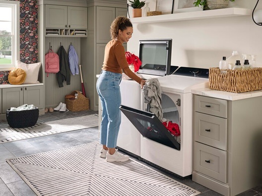 A woman moving laundry from her washer to her dryer.