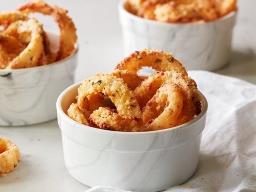 Crispy golden onion rings displayed in white ramekins