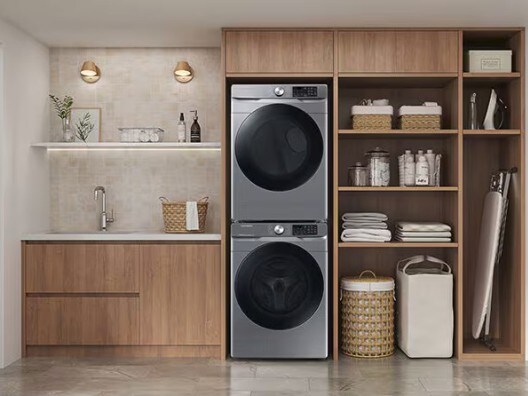 Neat and organized laundry room with a stacked washer and dryer, shelving, and a sink