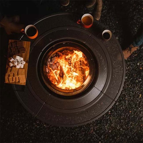 An aerial view of a fire pit with mugs and a platter of smores supplies around it.