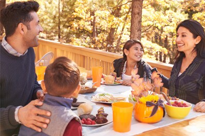 A family of four eating outside on a deck in autumn