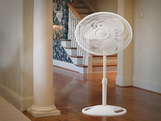 A pedestal fan sitting in a hallway.