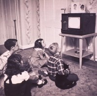Black and white 1950s photo of children sitting on the floor in front of a vintage TV