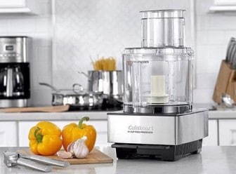 Cuisinart food processor in a kitchen with yellow peppers and garlic in the foreground