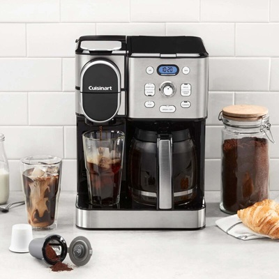 A coffee machine making a single cup of coffee with a full pot of coffee next to it.