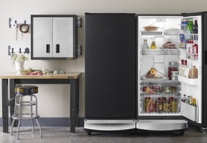 Refrigerator inside garage amongst worktable and cabinets