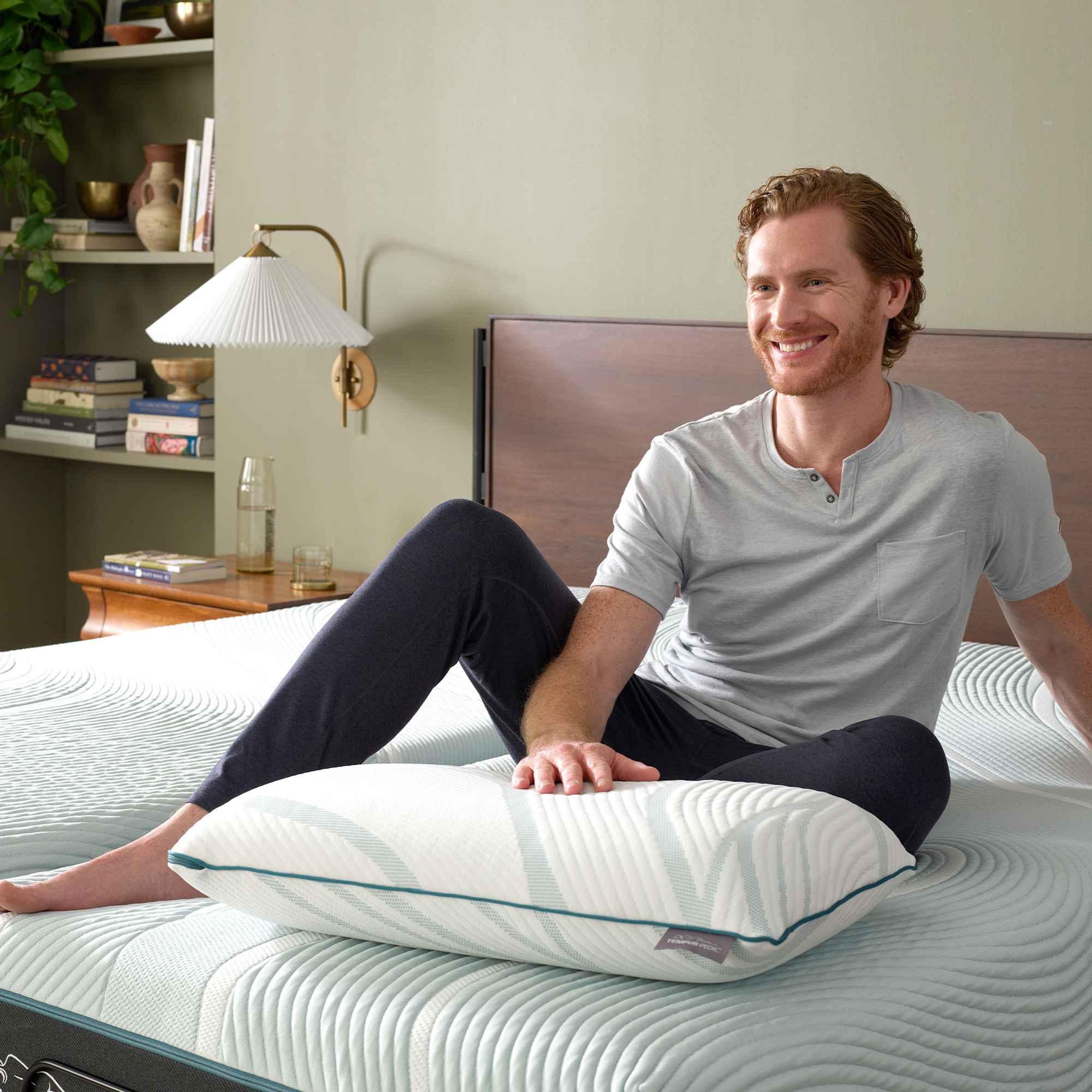 Man relaxing on a bed with a Tempur-Pedic pillow.